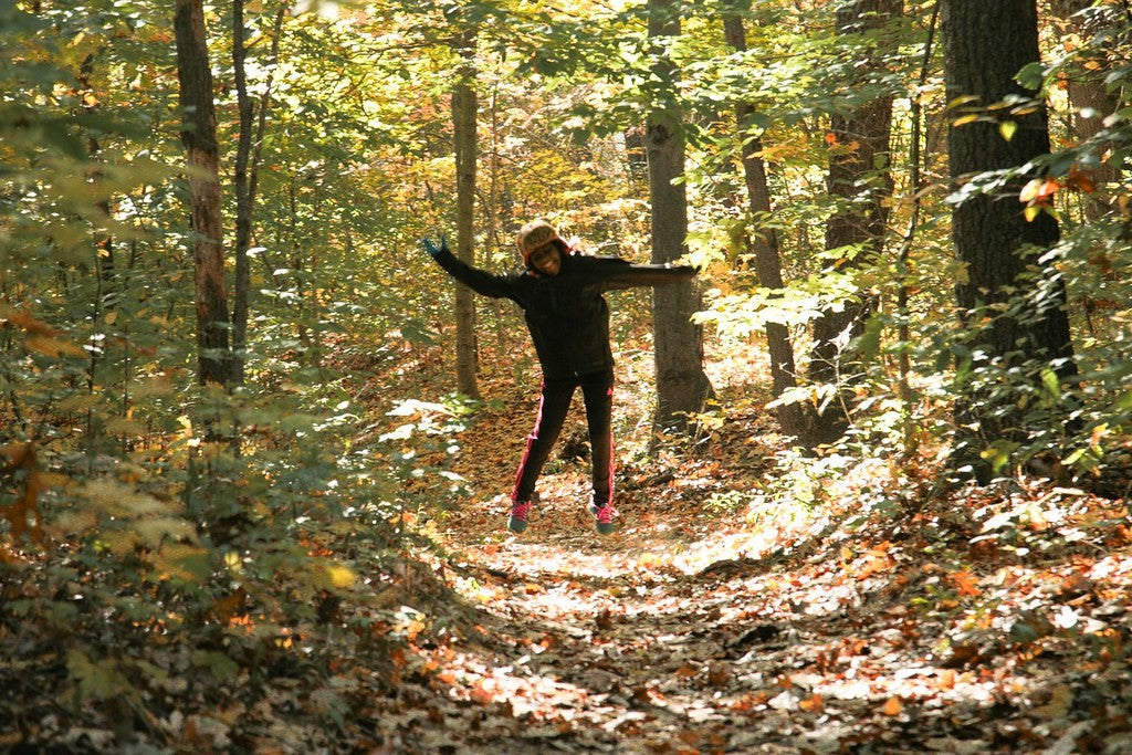 Girl stand in the middle of a trail in the woods